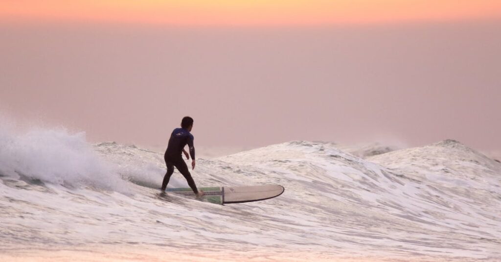 Marketing para Empresas de Actividades al Aire Libre en Colombia: Estrategias que Generan Reservas Reales 2 A surfer gracefully rides waves during a stunning summer sunset.